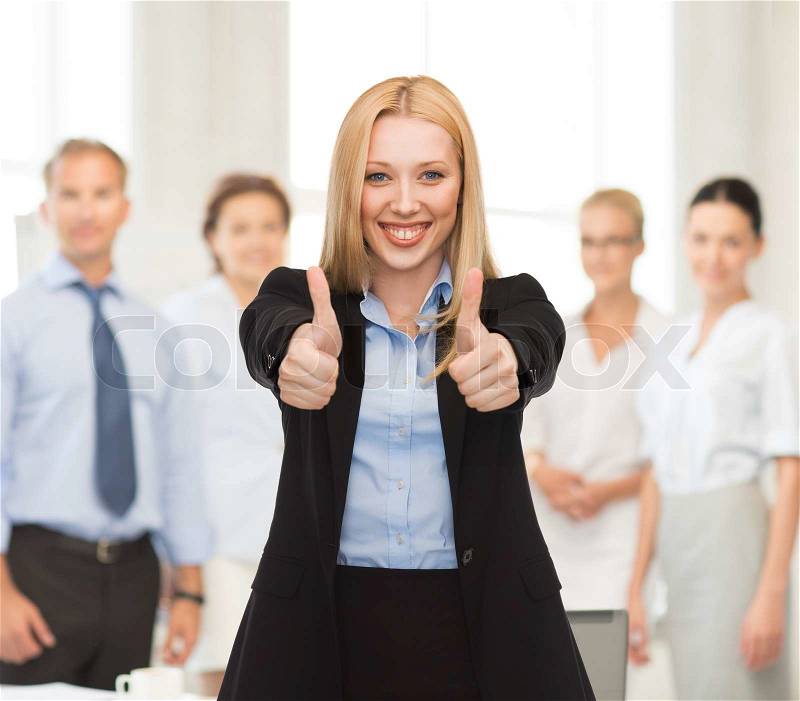 Young businesswoman with thumbs up in office, stock photo