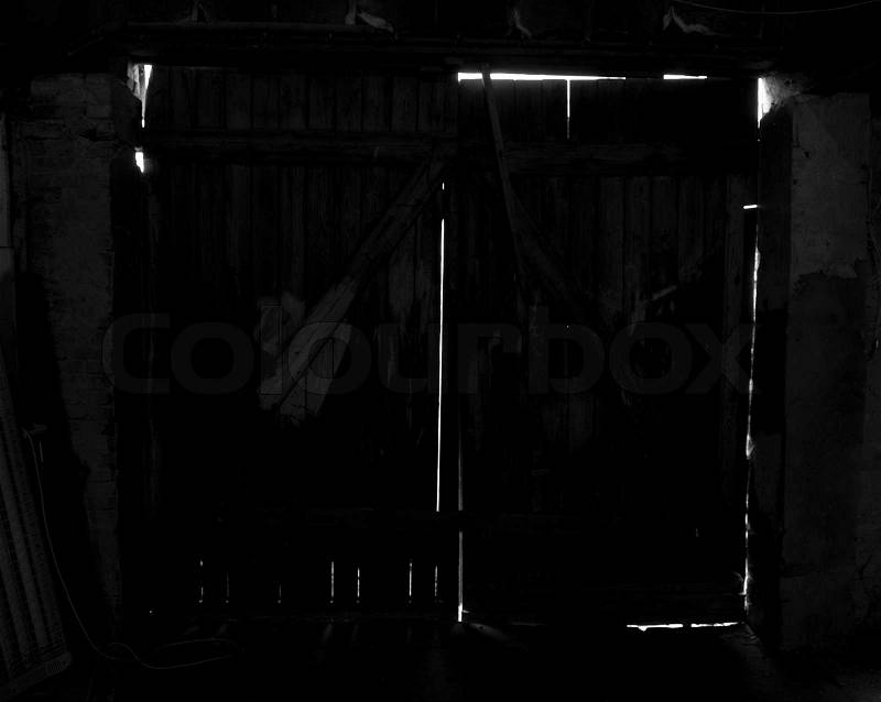 Inside a dark room, looking at the cracks in a old door, stock photo