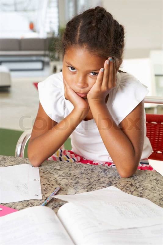 Fed Up Girl Doing Homework In Kitchen, stock photo