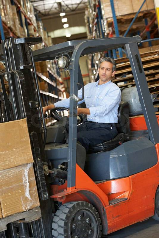 Man Driving Fork Lift Truck In Warehouse, stock photo