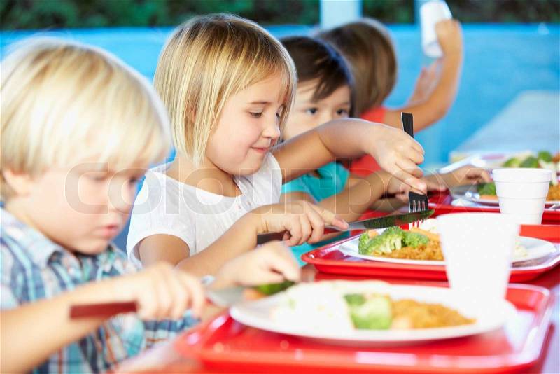Elementary Pupils Enjoying Healthy Lunch In Cafeteria, stock photo