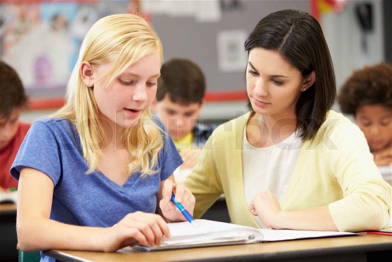 Teacher Reading With Female Pupil In Class, stock photo