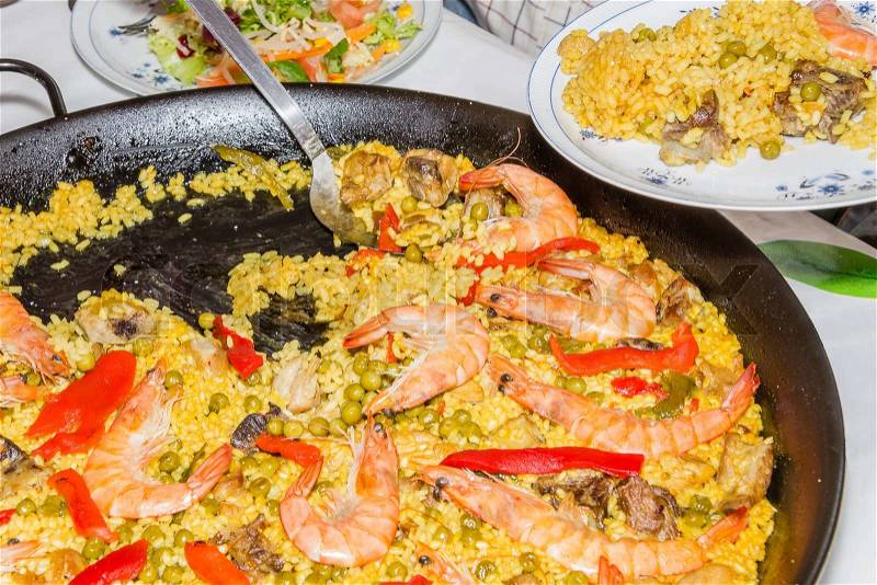 Serving traditional spanish paella cooked in a pan, with yellow rice and seafood, stock photo