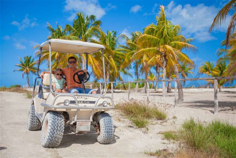 Dad with his two daughters driving golf cart at tropical country, stock photo