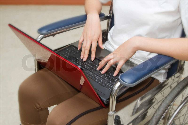 Disabled woman using a laptop in her wheelchair,concept education learning disabilities, stock photo