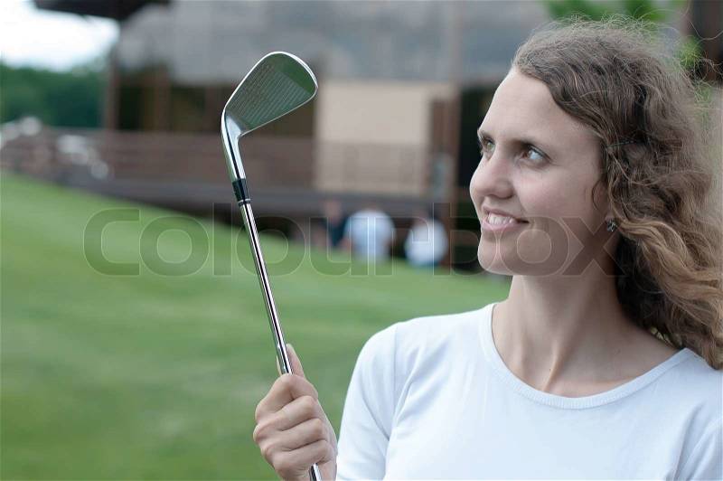 Girl golf player teeing off with driver from tee box, front view, stock photo