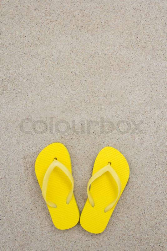 Yellow flip flops on the white beach sand, stock photo