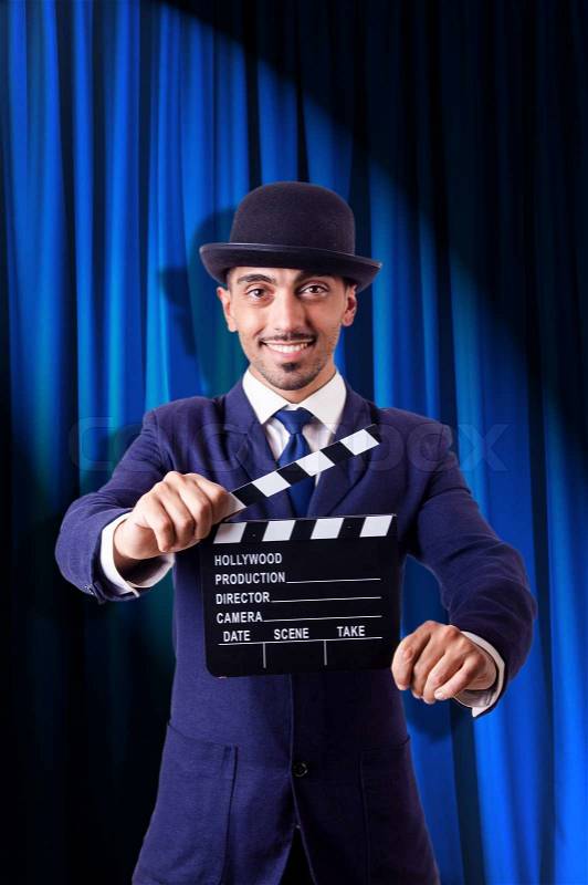 Man with movie clapper on curtain background, stock photo