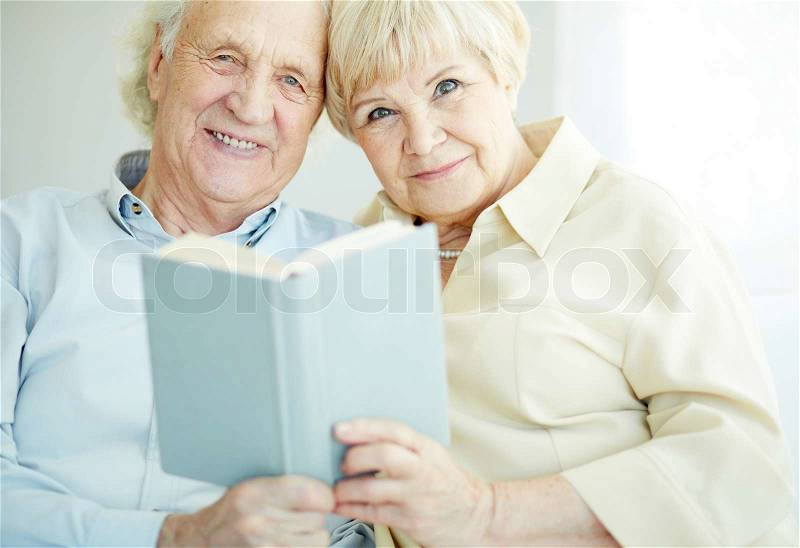 Portrait of a candid senior couple reading book together, stock photo