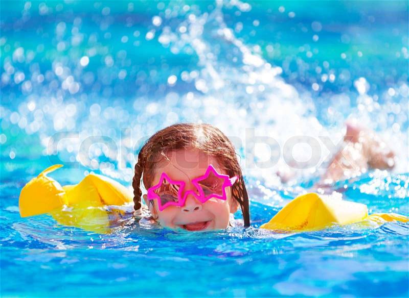 Closeup portrait of cute little arabic girl swimming in the pool, happy child having fun in water, beach resort, summer vacation and holidays concept, stock photo