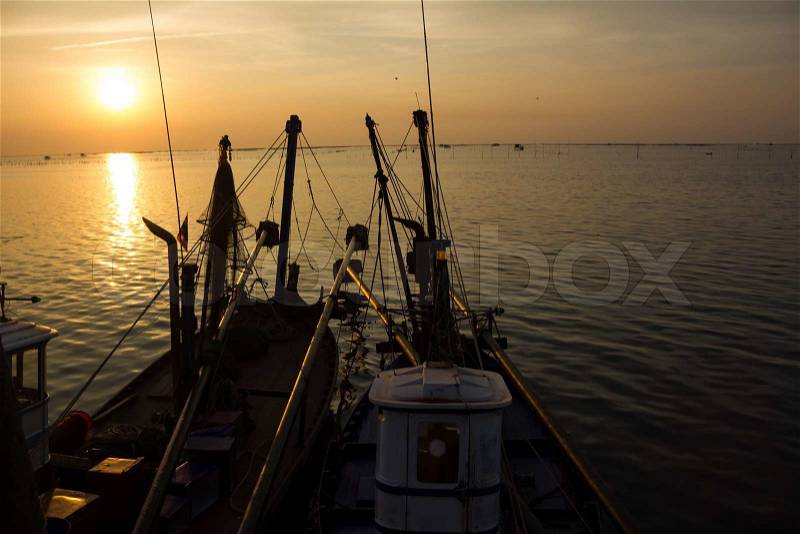 Fishing boats anchored in the sea, floating peacefully in the evening, stock photo