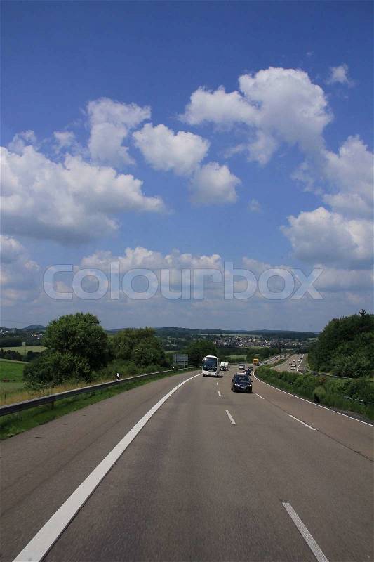 Blue sky with clouds and coach and cars driving over the highway for vacation to a foreign land in summertime, stock photo
