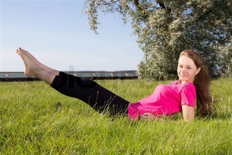 Young woman exercising in park on the grass, stock photo