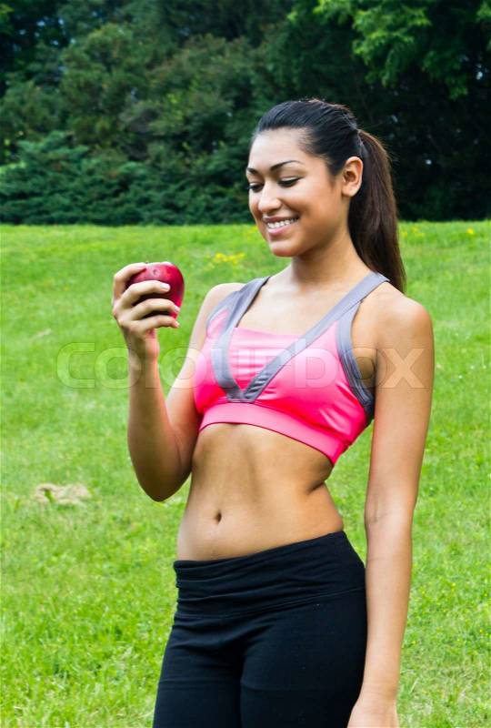 Fit young woman with an apple in the park, stock photo