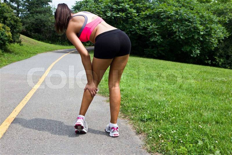 Young woman with running injury on calf, stock photo
