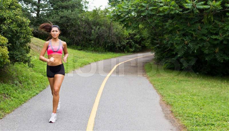 Smiling young woman running for fitness, stock photo