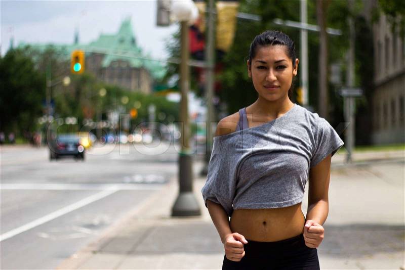 Fit young woman running on a busy city street, stock photo