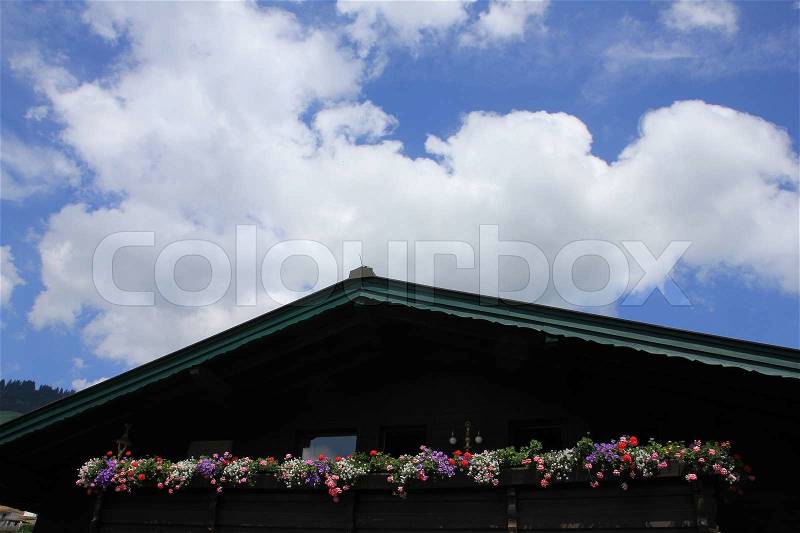 Blue sky, clouds and blooming plants in flower boxes on the balcony of the house in the summer, stock photo
