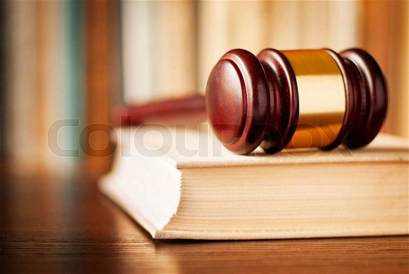 Conceptual image of law enforcement, justice and sentencing with a closeup view of a wooden judges gavel lying on a law book, stock photo