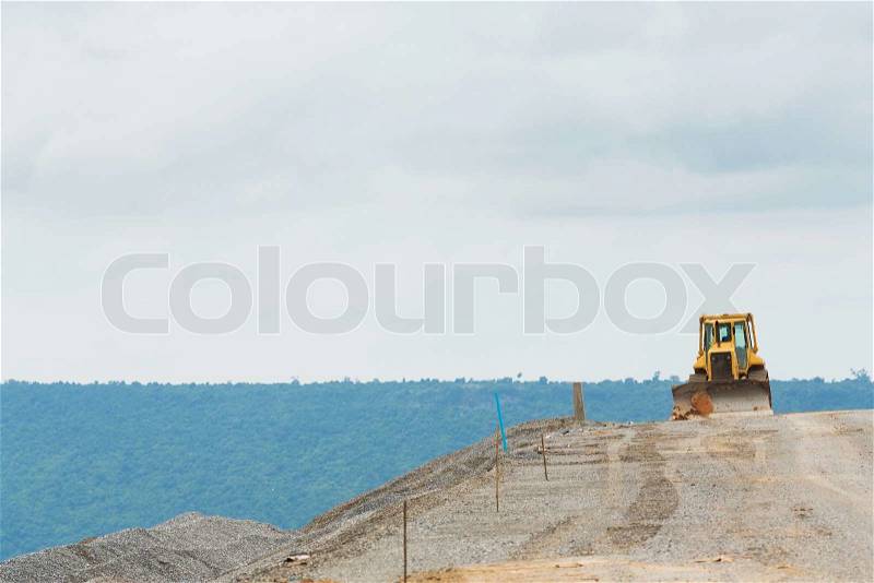 Yellow color backhoe working on dam crest , stock photo