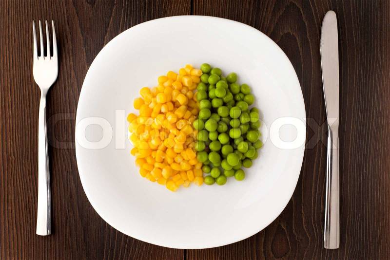 Heap of corn seeds and peas on a white plate. Diet concept, stock photo