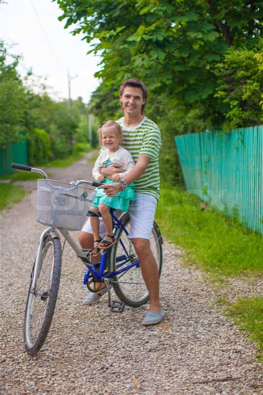Young father and cute little daughter riding bikes together, stock photo