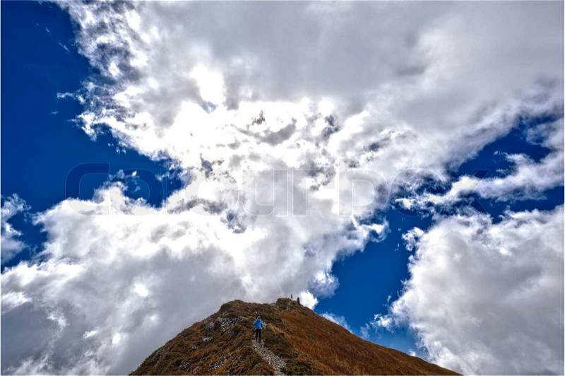 Climbing the mountain tourists under the clouds, stock photo