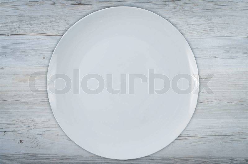 Empty white plate on white wooden table, stock photo