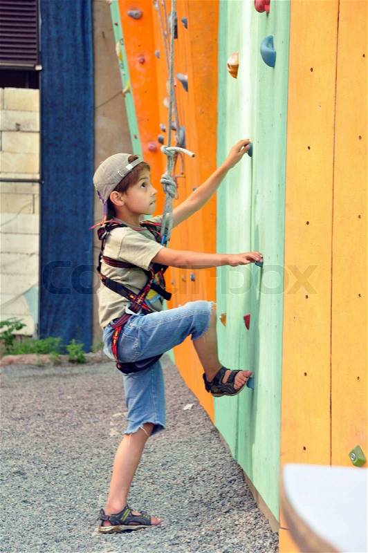6 years old kid climbing up the wall, stock photo