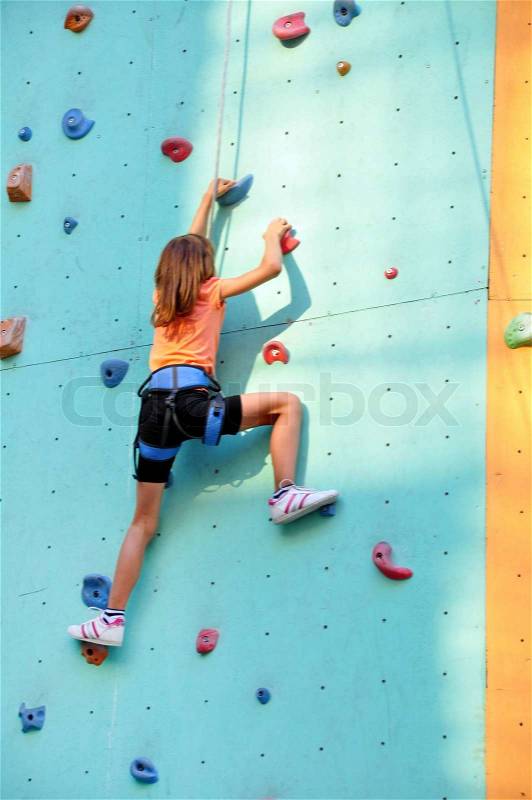 8 years old girl climbing up the wall, stock photo