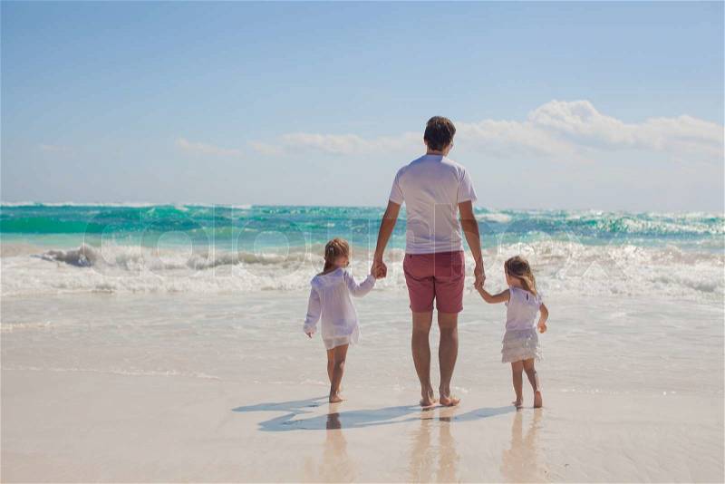 Back view of happy father and his adorable little daughters walking on sunny day, stock photo