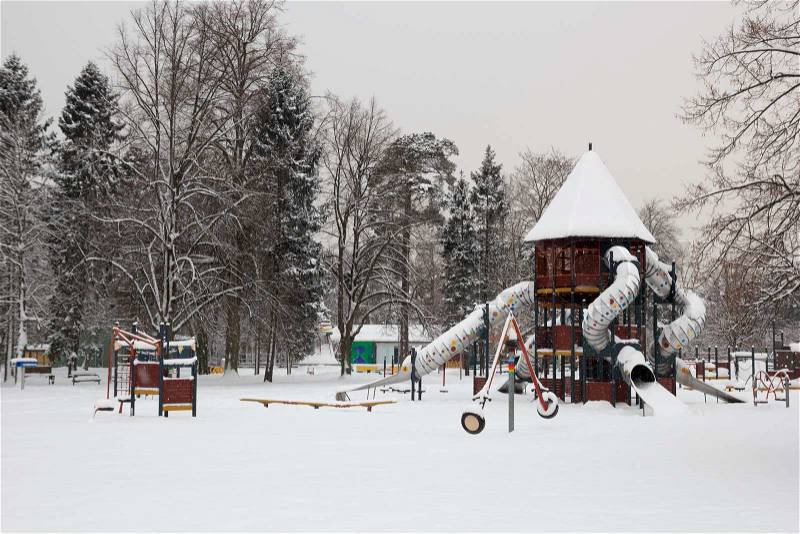 Snow covered children playground in city park, stock photo