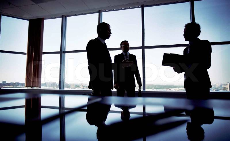 Shady image of a manager discussing business matters with her subordinates, stock photo
