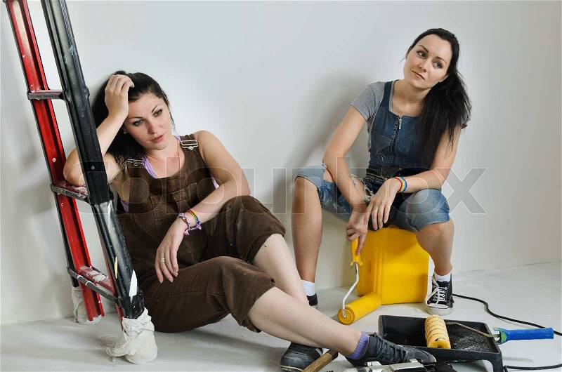 Exhausted women taking a break from renovating relaxing on the floor surrounded by a variety of tools and equipment, stock photo