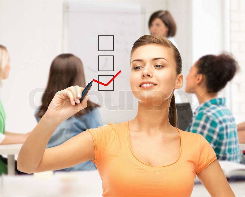 Education and technology concept - student drawing checkmark on virtual screen, stock photo