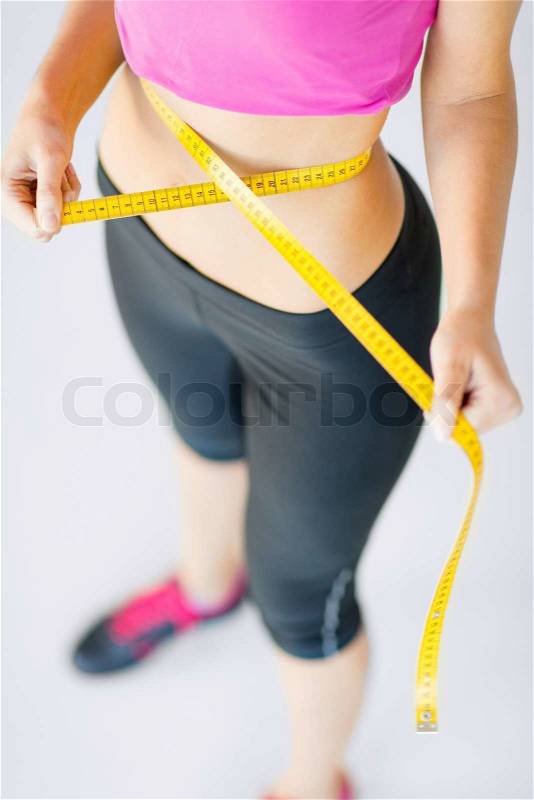 Sport and diet concept - trained belly with measuring tape, stock photo