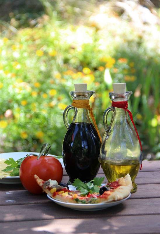 Piece of pizza in the summer garden table with olive oil and vinegar sauce, stock photo