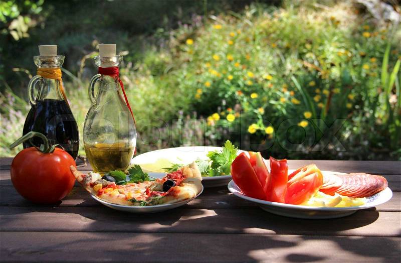 Piece of pizza in the summer garden table with olive oil and vinegar sauce, stock photo