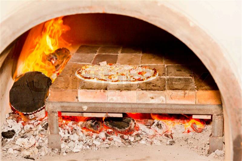 Pizza cooking in a tradition fire wood oven, stock photo