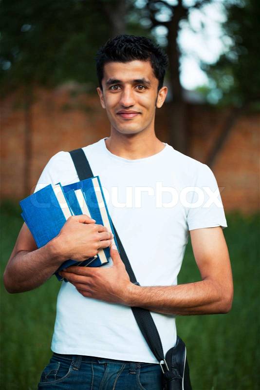 Arab male student with books outdoors looking very happy, stock photo