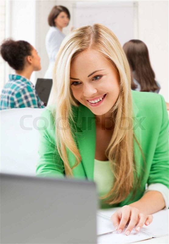 Education and internet concept - student girl with laptop in college, stock photo