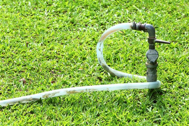 Close up tab water valve and plastic hose on green lawn, stock photo