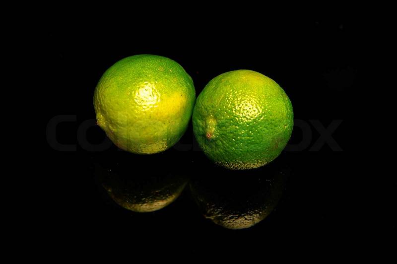 Lime fruit on reflecting black table, stock photo