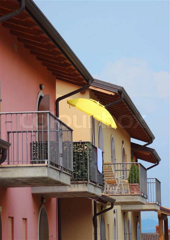 Yellow parasol on balcony with colorful house, stock photo