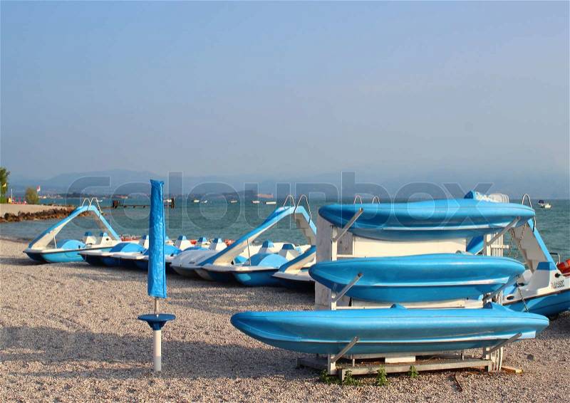Blue boats and water cycles at rubble beach in the morning, stock photo