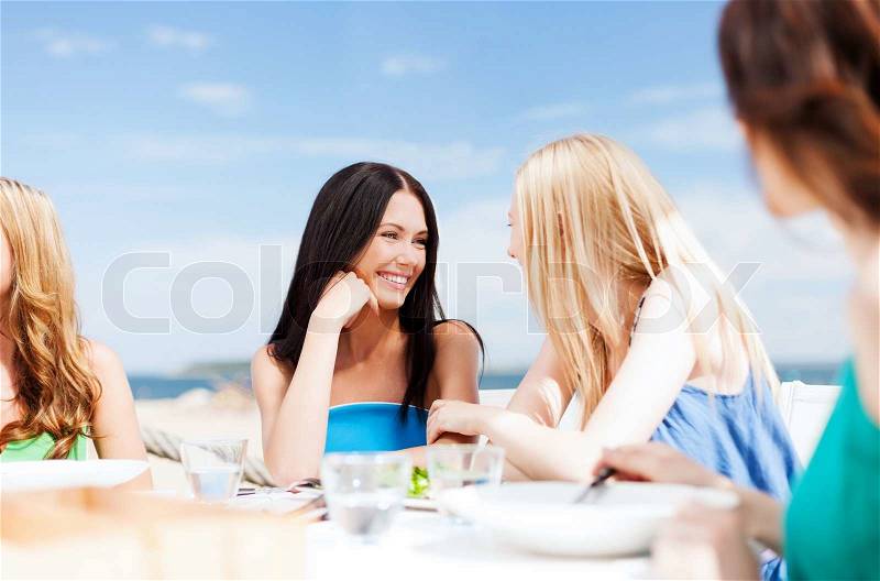 Summer holidays and vacation - girls in cafe on the beach, stock photo