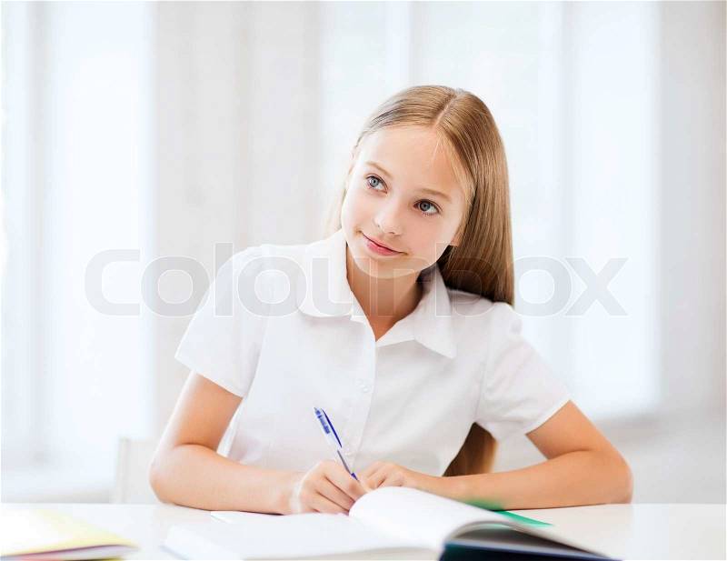 Education and school concept - little student girl studying at school, stock photo