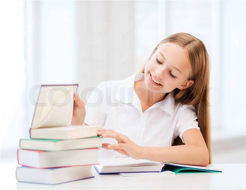 Education and school concept - little student girl studying and reading books at school, stock photo