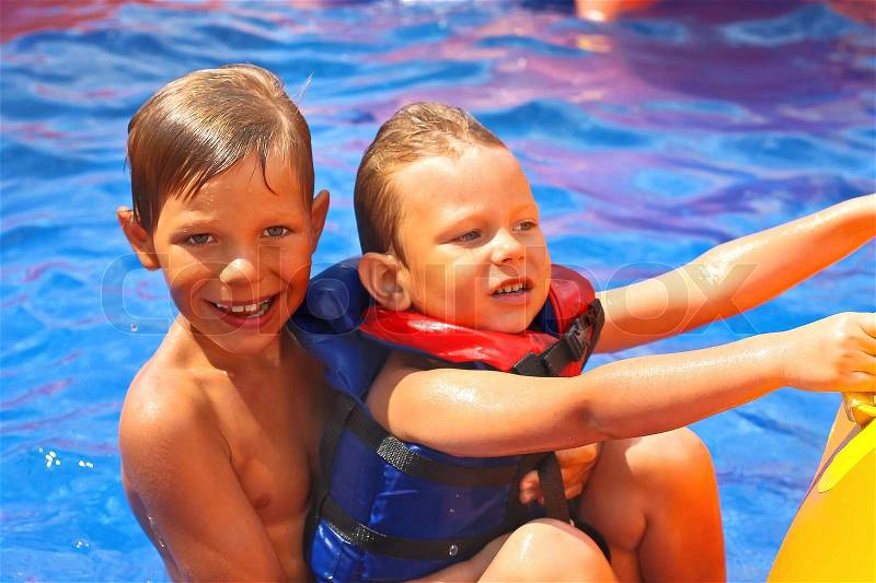 Two brothers in swimming pool at the water park, stock photo