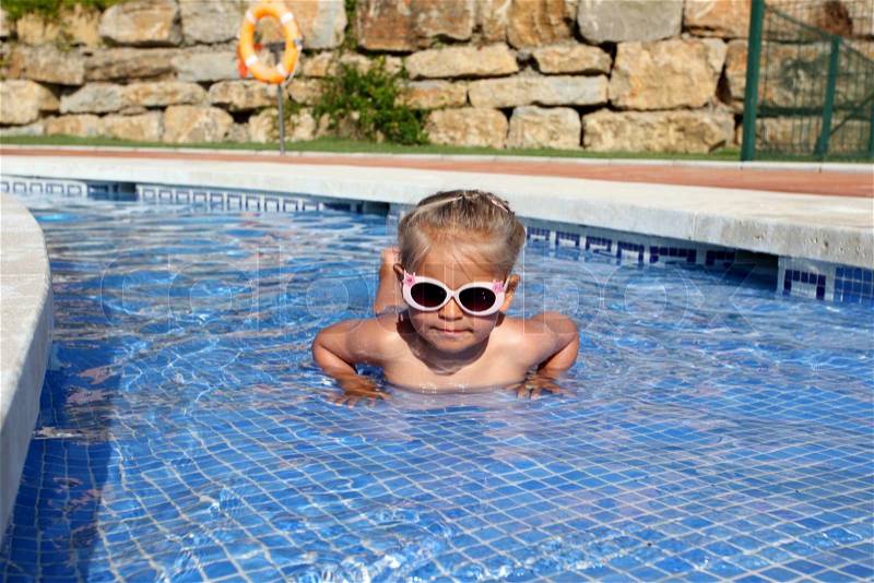 Little girl with sun glasses having fun in the pool, stock photo